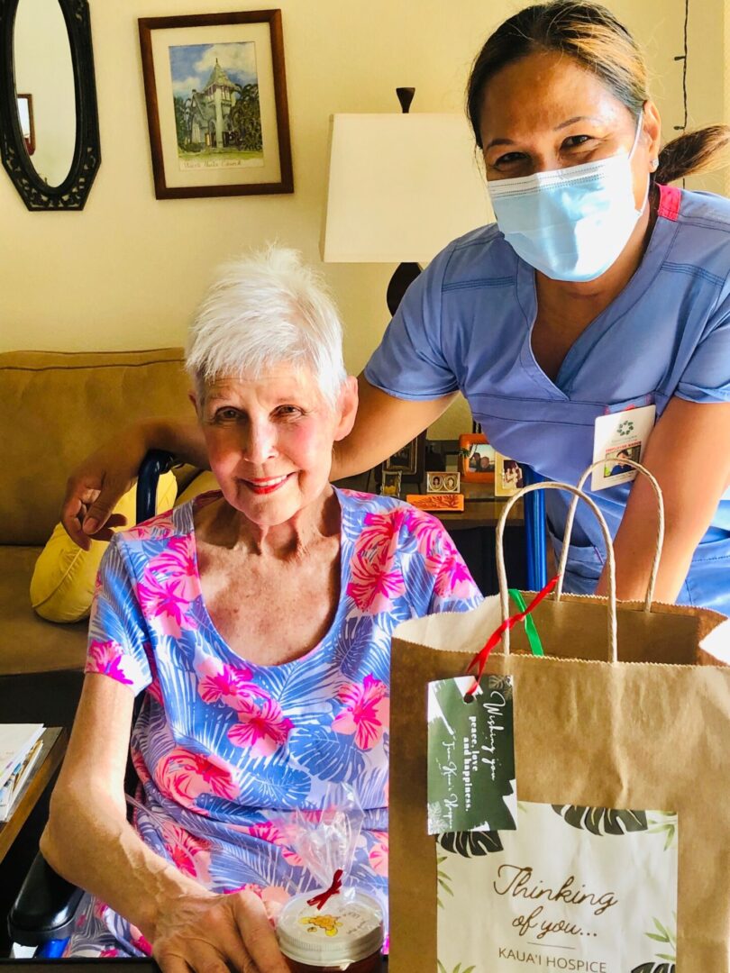 Masked caregiver visiting smiling senior woman with gift