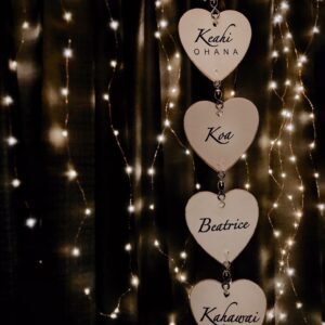 Heart-shaped decorations with names hang against a backdrop of warm string lights.