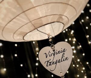 Heart-shaped tag with "Virginia Tangalin" under warm lights.